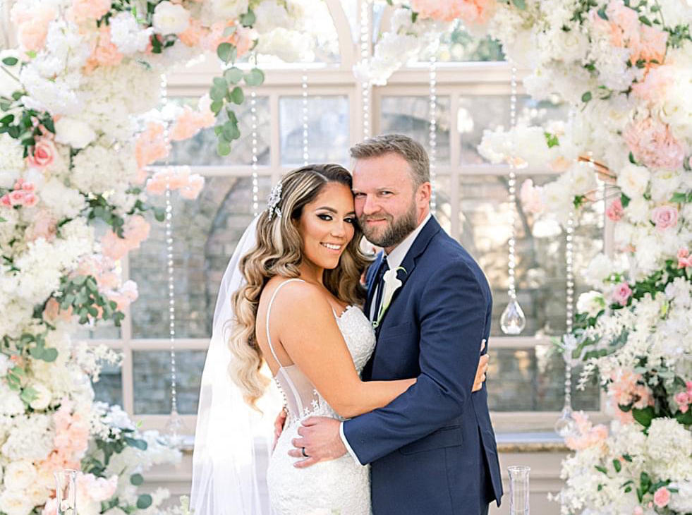 Bride and Groom in an arc of flowers at The Wedding
